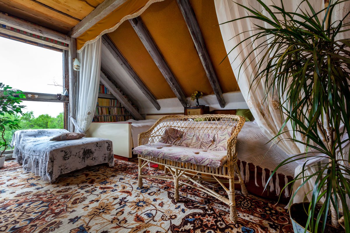 ložnice ve stodole s postelí, pleteným sezením a květinovým kobercem