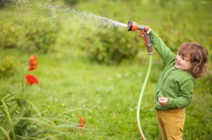 malé dítě zalévá zahradu rozstřikovací hlavicí