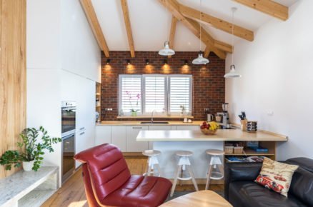 obývací pokoj s kuchyní s dřevěným nábytkem, koženými sedačkami, cihlovým obkladem a přiznanými trámy