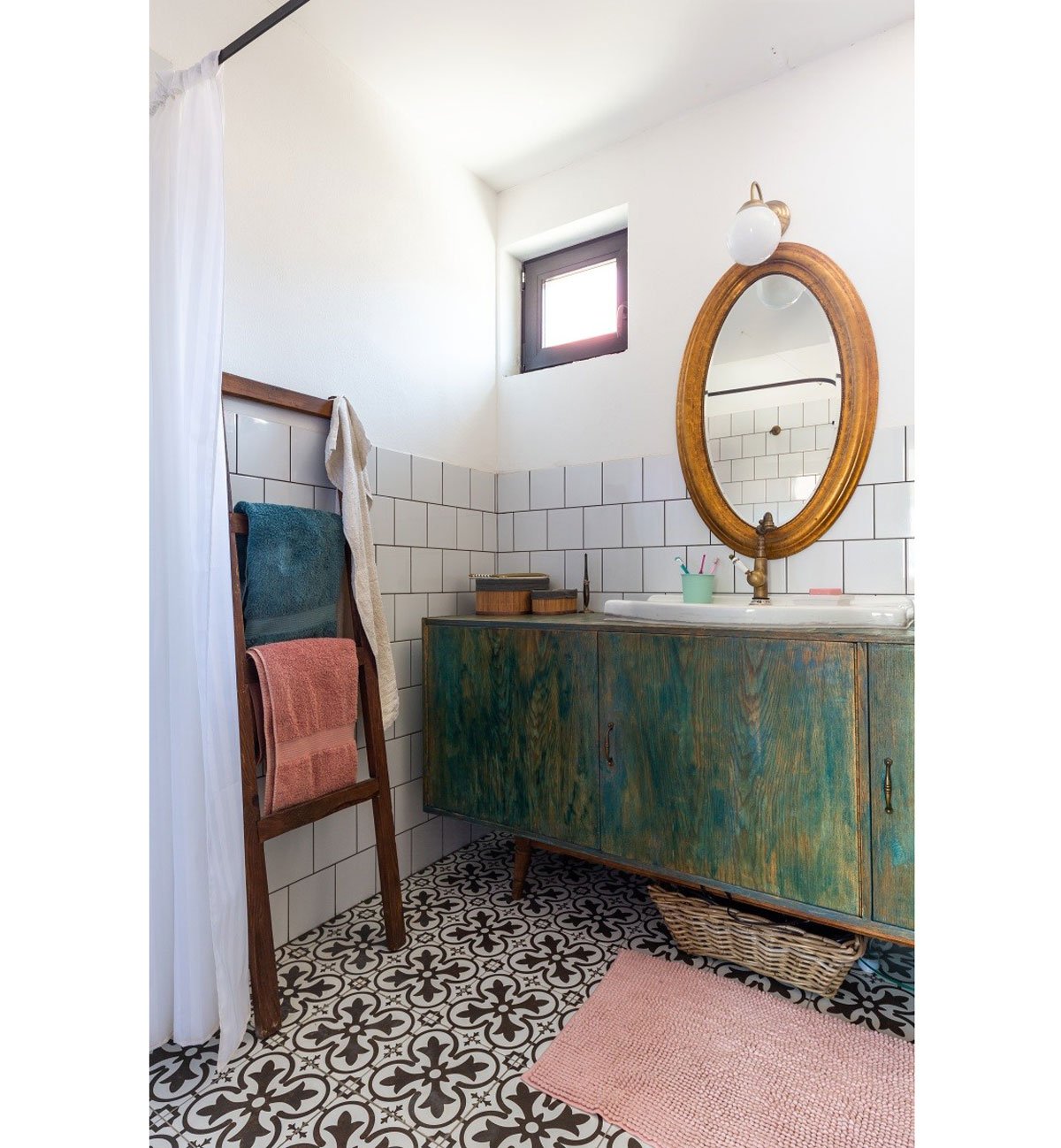 koupelna se zelenou lazúrovanou skříňkou, mosazným zrcadlem a vzorovanou podlahou