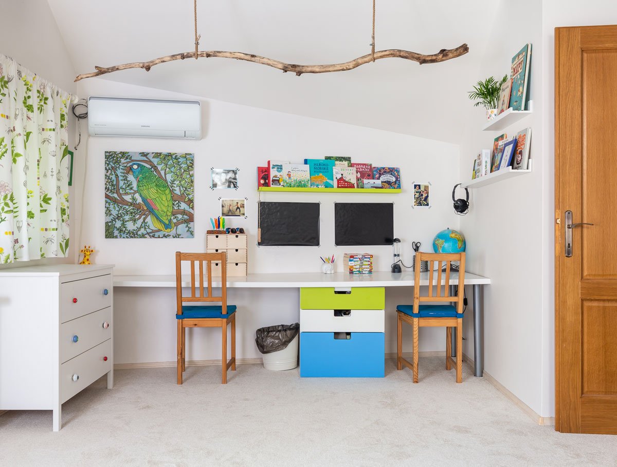 dětský pokoj s nábytkem v bílé, modré a zelené barvě, s komodou, pracovním stolem, stoličkama, barevnými závěsi a větvou zavěsenou ze stropu