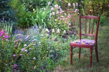 Jak vytvořit romantickou květinovou zahradu: dřevěná židle vedle květinových záhonů