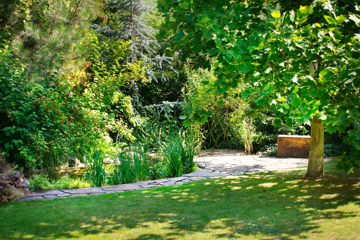 Pohled do zahradní části s chodníkem z kamene, jezírkem a altánkem z vrby.