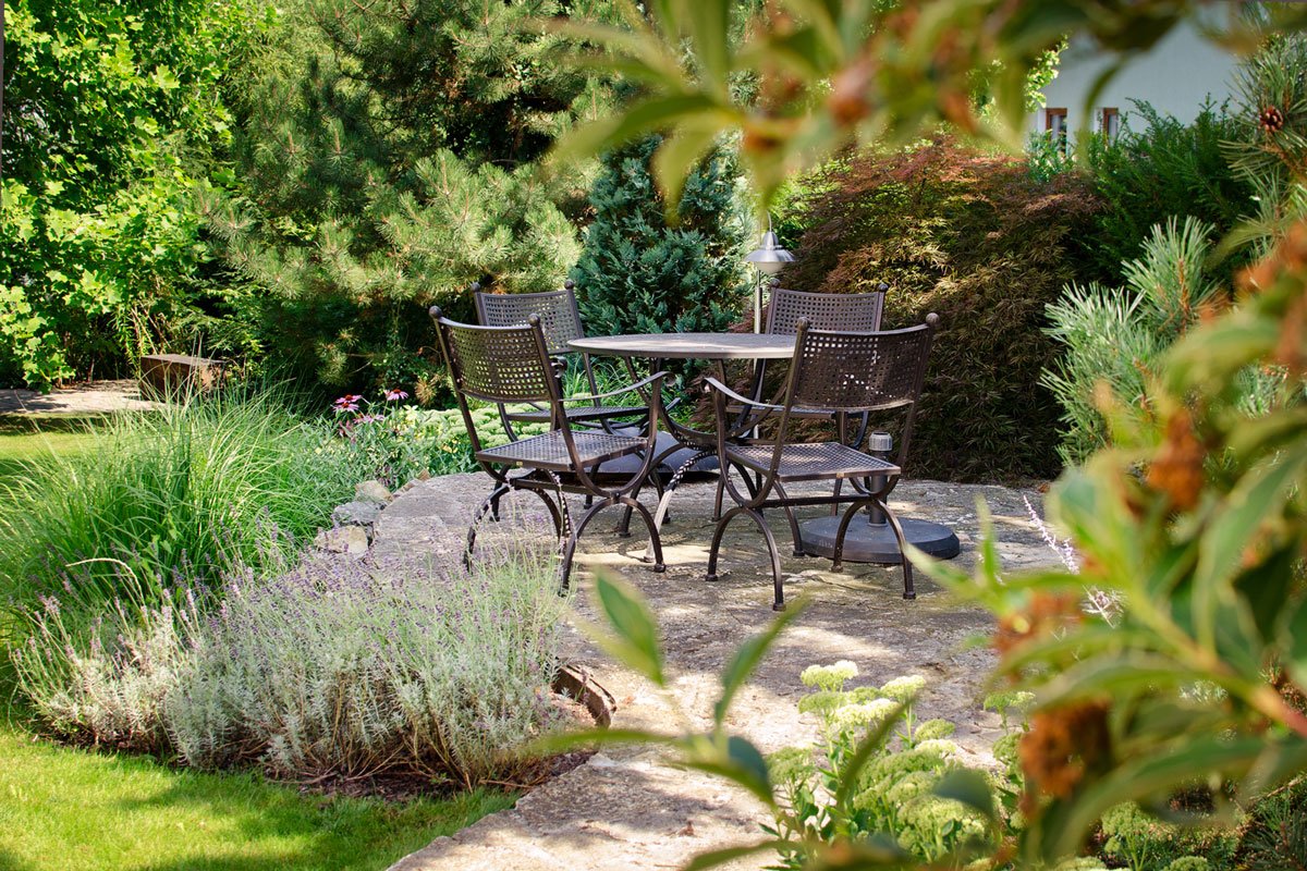zahrada s andezitovou terasou se sezením, obklopena trvalkovými záhony