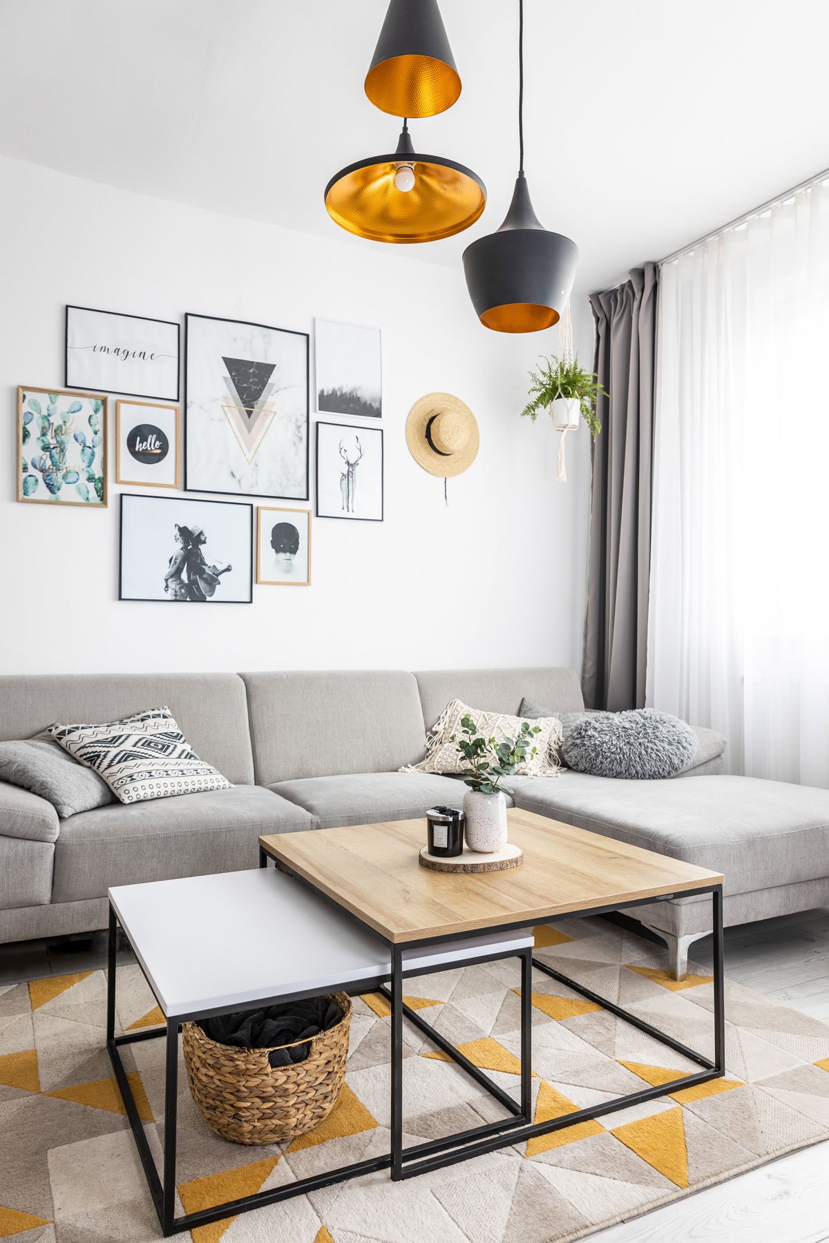 Obývací pokoj ve skandinávském stylu se šedou sedací soupravou a kovovými stoly