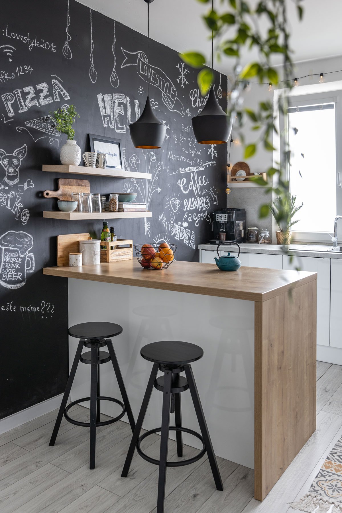 Kuchyně s černou stěnou a ostrůvkem s barovými židlemi