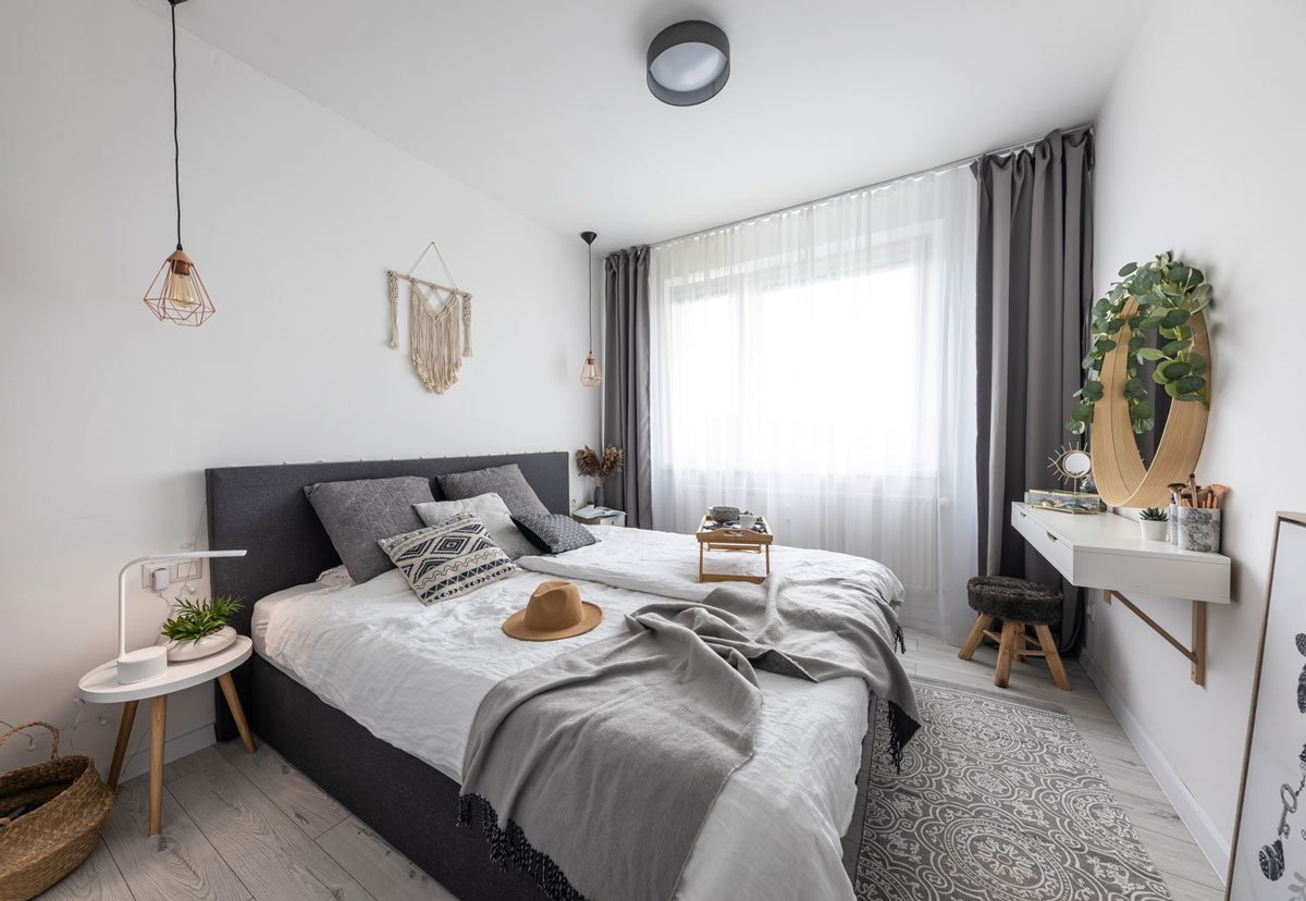 Ložnice ve skandinávském stylu s čalouněnou postelí a odstínech šedé