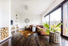 obývací pokoj s ručně malovaným bílým dřevěným obkladem, tmavou podlahou, výklenkem ve zdi sloužícím na odkládání dřeva a policemi s úložnými prostormi zasazenými přímo do zdi