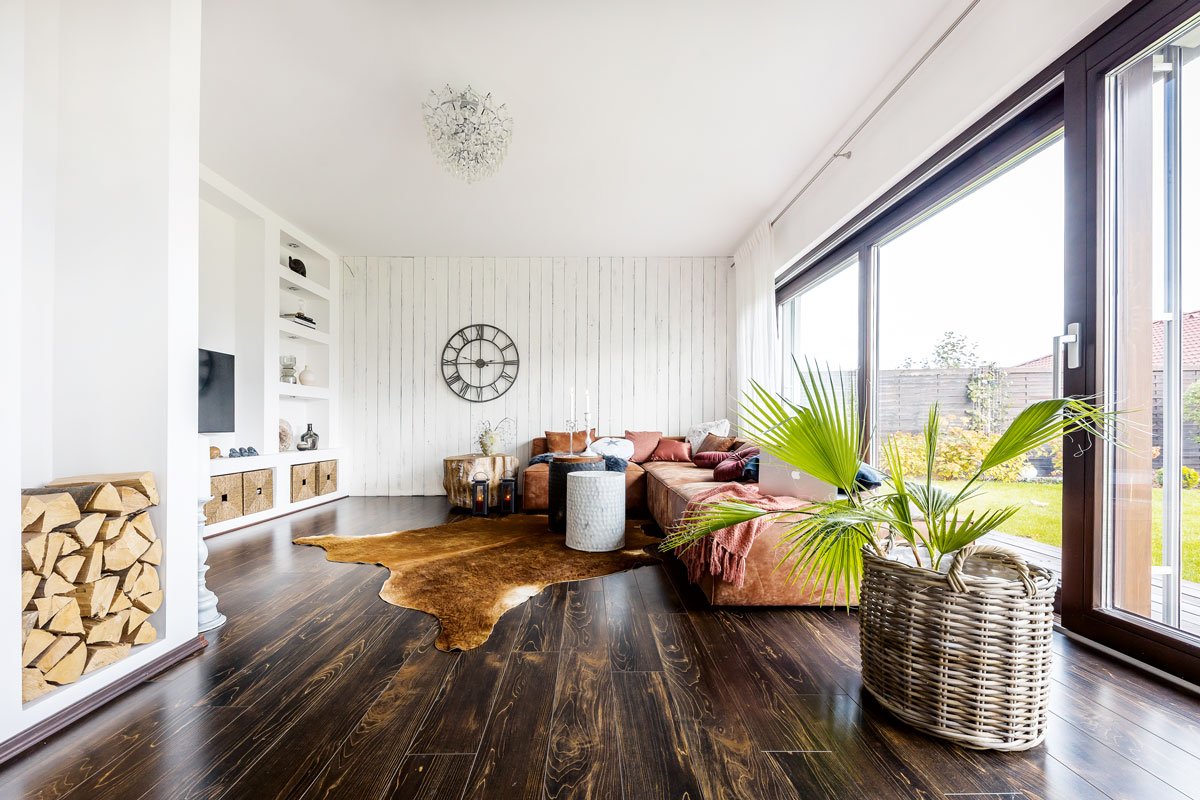 obývací pokoj s ručně malovaným bílým dřevěným obkladem, tmavou podlahou, výklenkem ve zdi sloužícím na odkládání dřeva a policemi s úložnými prostormi zasazenými přímo do zdi