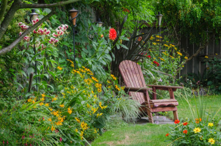 okrasná zahrada s trvalkovými záhony a dřevěnou židlí