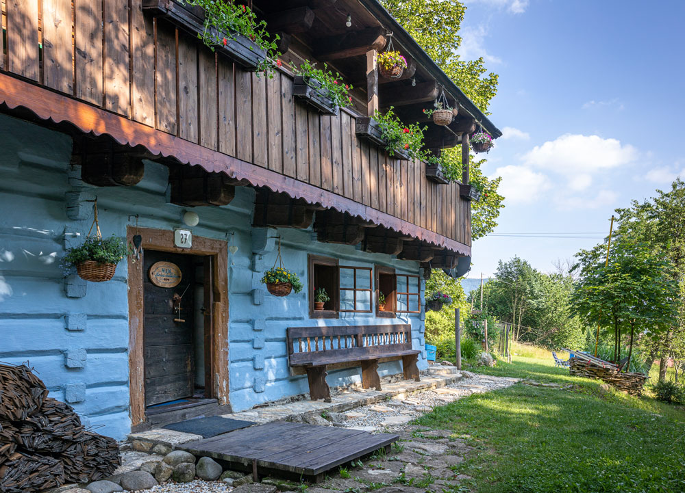 modrá tradiční chalupa s dřevěnou verandou