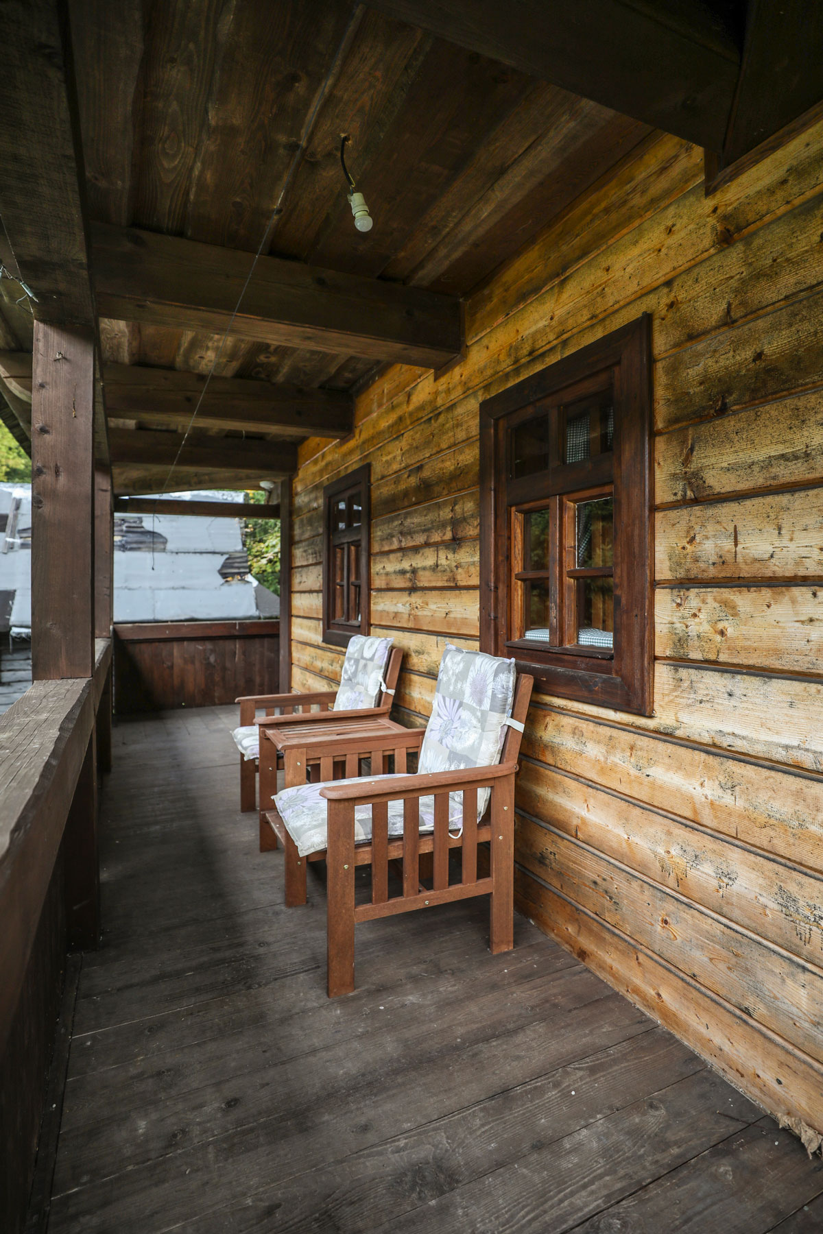 veranda na chalupě s dřevěným stolem a židlemi