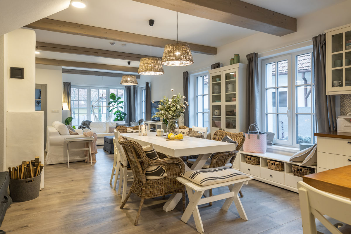 jídelna ve skandinávském venkovském stylu s masivním stolem a různorodým sezením z proutěných křesel, taburetek a dřevěných židlí