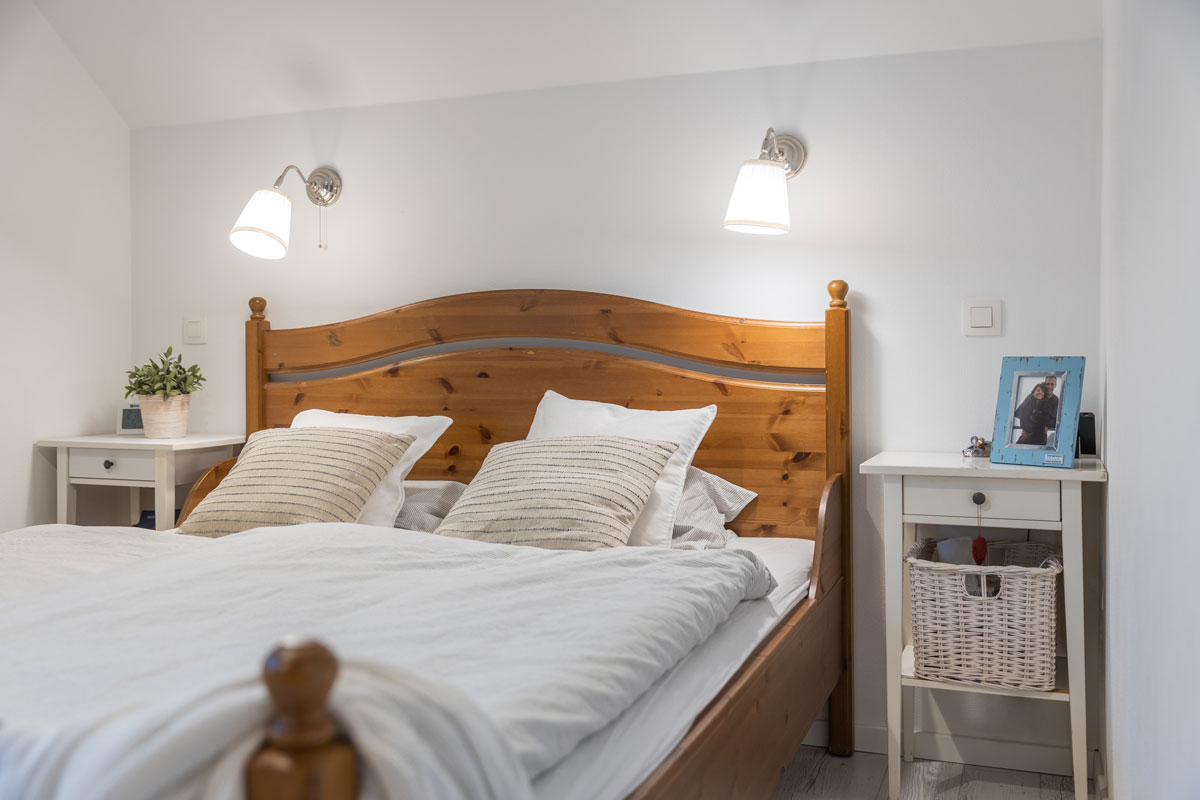 Ložnice s dřevěnou postelí a bílými nočními stolky