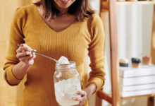 žena nabírá sodu bikarbonu ze skleněné nádoby