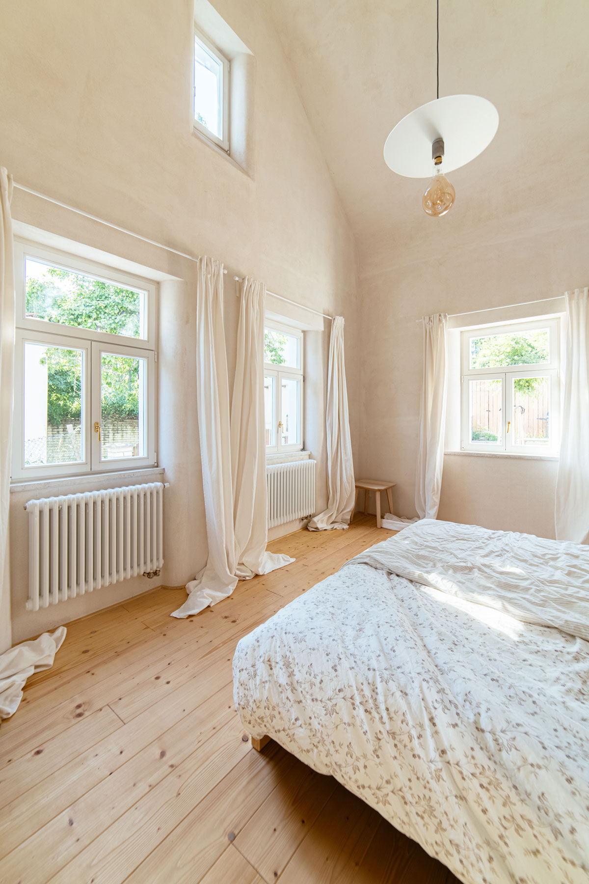 romantická ložnice na chalupě s vysokými stropy a dřevěnou podlahou