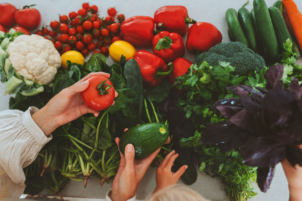 ruce ženy a dítěte s různými druhy zeleniny