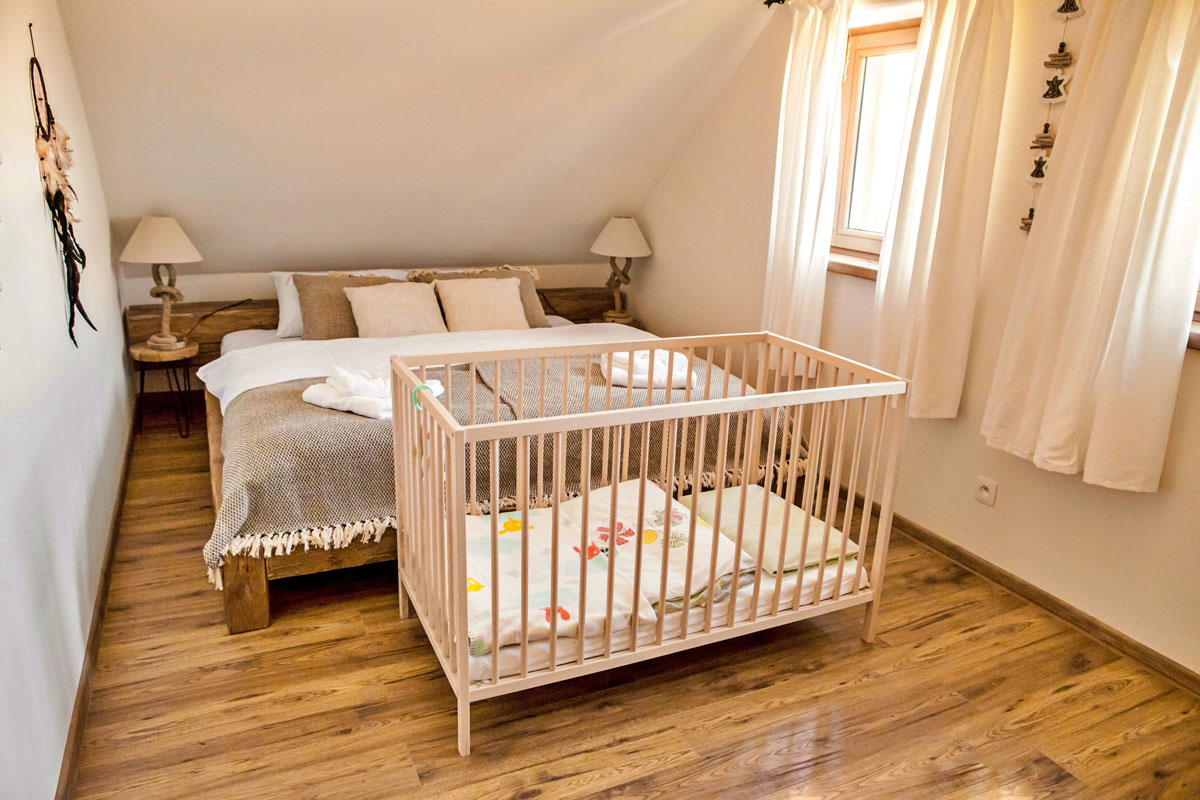 ložnice s postelí z masivního dřeva a postílkou pro dítě