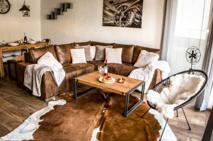 interiér obývacího pokoje v chalupě Urbanovy sestry v industriálním stylu s koženou sedačkou, kravskou kůži a křeslem