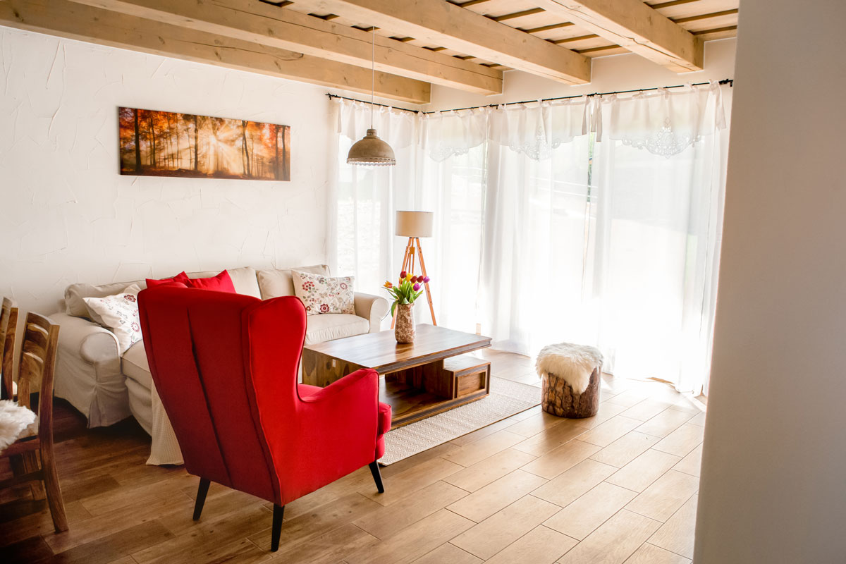 obývací pokoj chalupy s bílou pohovkou a červeným křeslem