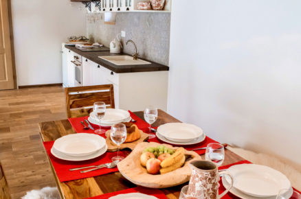 bílá venkovská kuchyň a jídelný stůl s červeným prostíráním