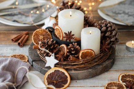 Vánoční rustikální dekorace ve tvaru věnce vyrobená z průtí, svíček, šišek, koření a sušených pomerančů