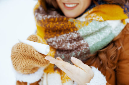 žena stojící v zimě venku si nabírá pleťový krém