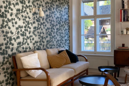 jednoduchý obývací pokoj na chalupě, na jedné ze stěn je tapeta s rostlinným motivem