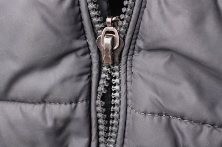 Zip na bundě s chybějícími zoubky na kolejničce