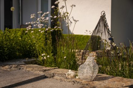 Kovová ptačí klícka s jemnou patinou důmyslně zakrývá šachtu na závlahový systém. V prostoru zahrady je zároveň vkusně zakomponováno více stylových, typicky venkovských dekorací převážně v bílé barvě.