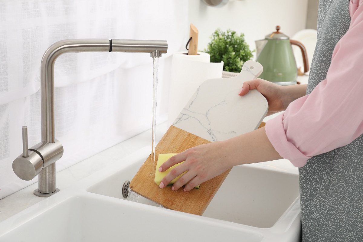 Woman,Washing,Cutting,Board,At,Sink,In,Kitchen,,Closeup