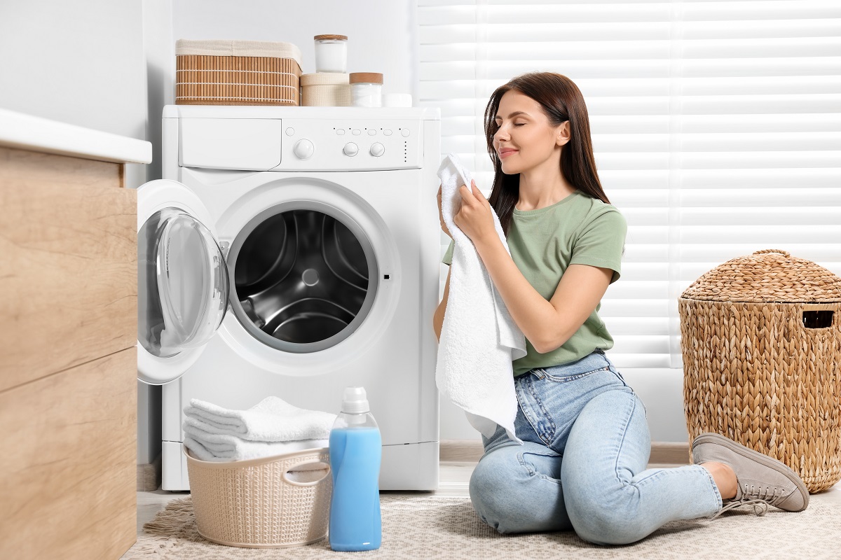 Woman,Smelling,Clean,Towels,Near,Washing,Machine,In,Bathroom