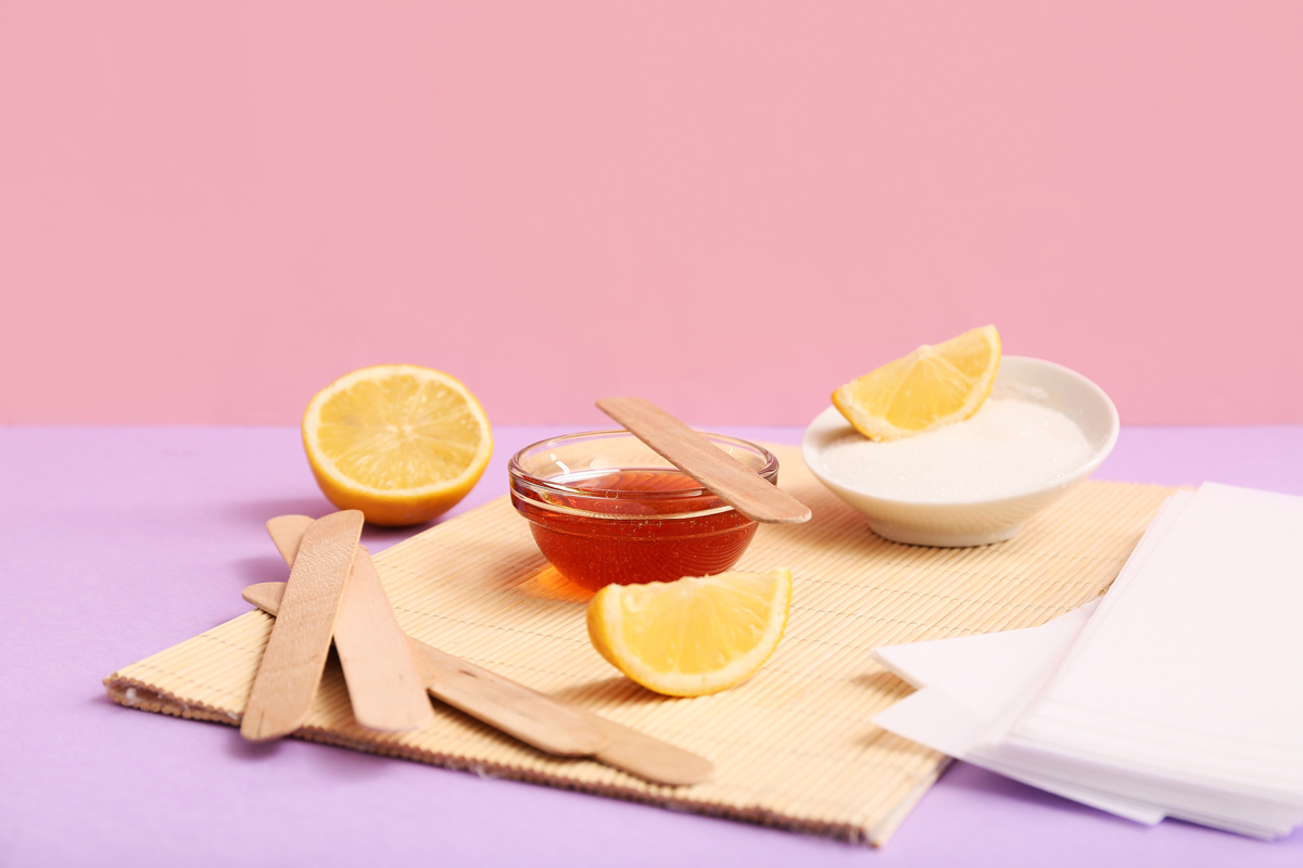 Ingredience na domácí cukrovou pastu: citron, cukr a miska s pastou na barevném podkladu.