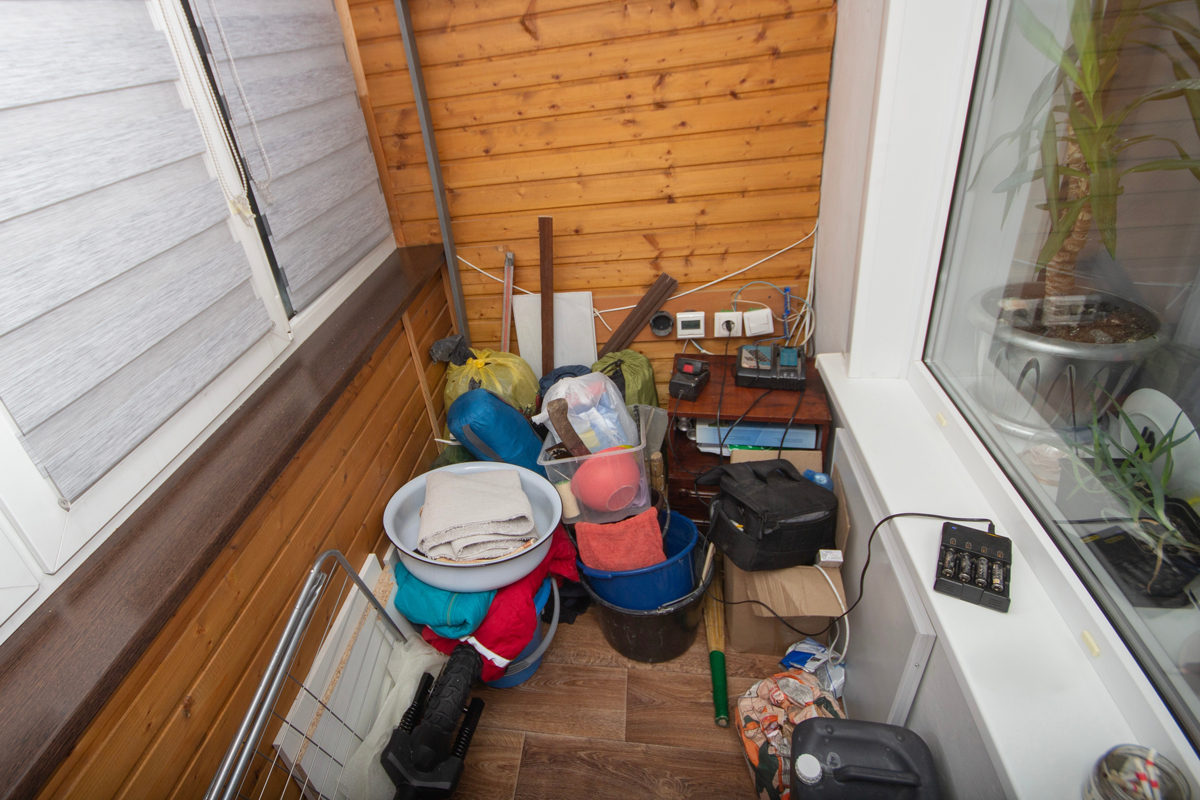 Balkon, zaprataný věcmi a plný nepořádku.