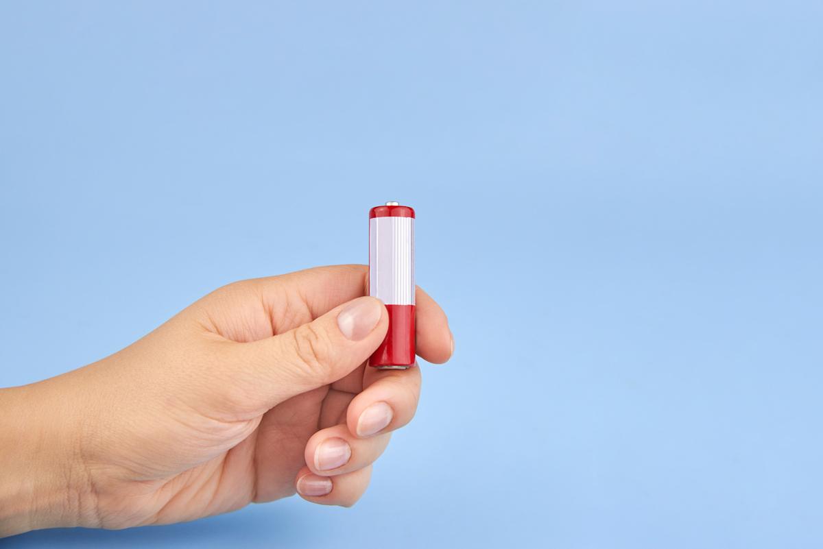 Ruka držící jednu tužkovou baterii, připravenou na drop test