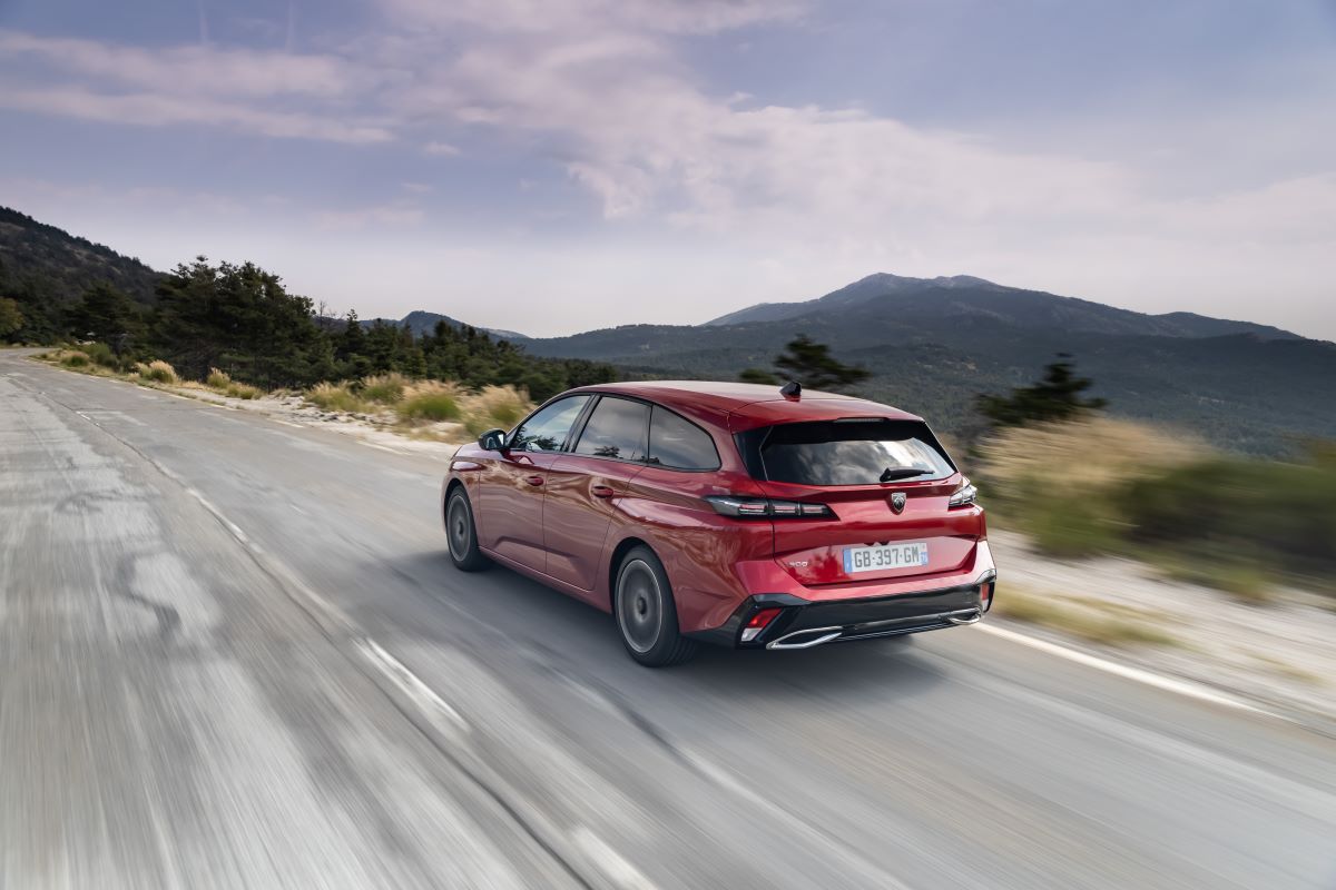 Zadní tříčtvrteční pohled v pohybu – červený Peugeot 308 SW na horské silnici.