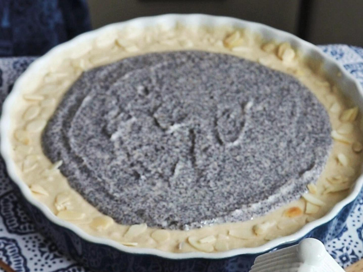 Těsto na makový koláč před pečením – domácí recept s mákem a plátky mandlí v keramické formě.