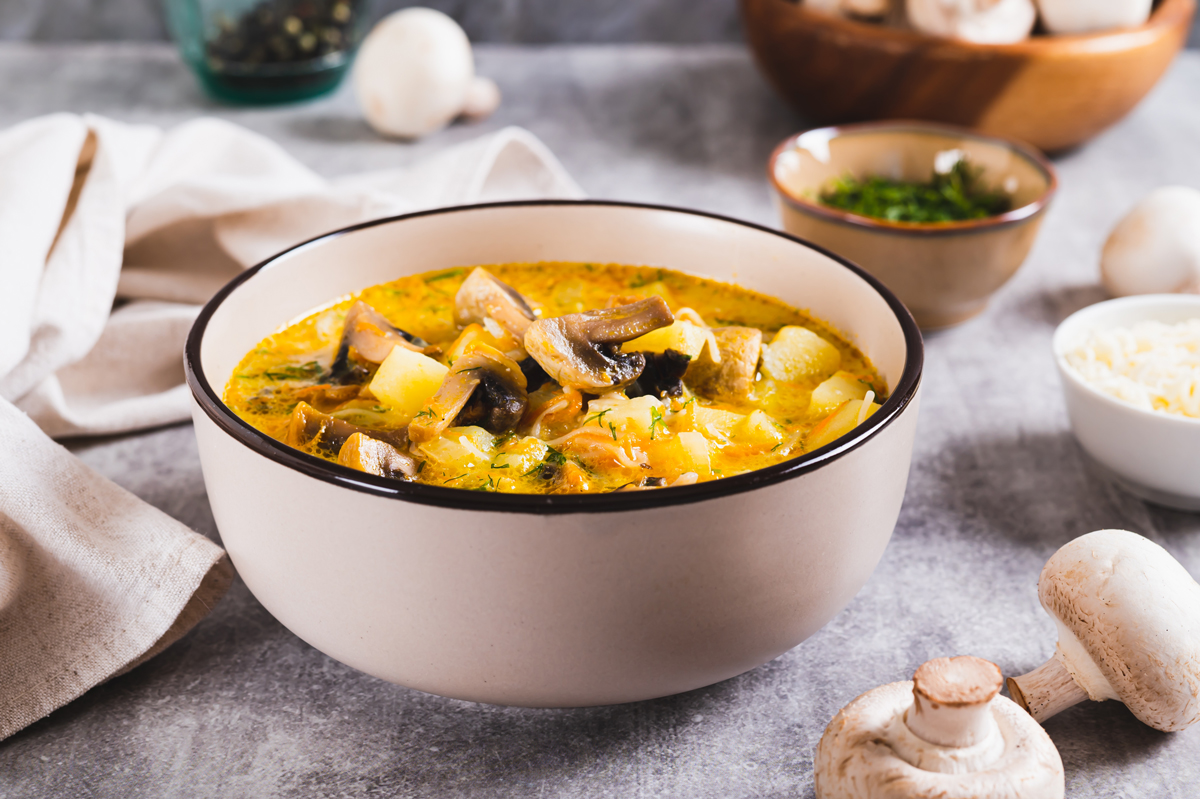 Miska s krémovou polévkou z divoké rýže, brambor a hub, ozdobená petrželí.