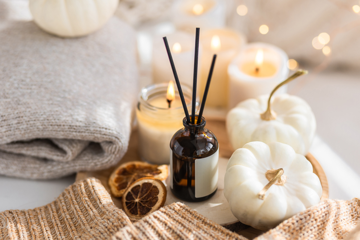 Podzimní dekorace se svíčkami, aroma difuzérem a mini dýněmi.