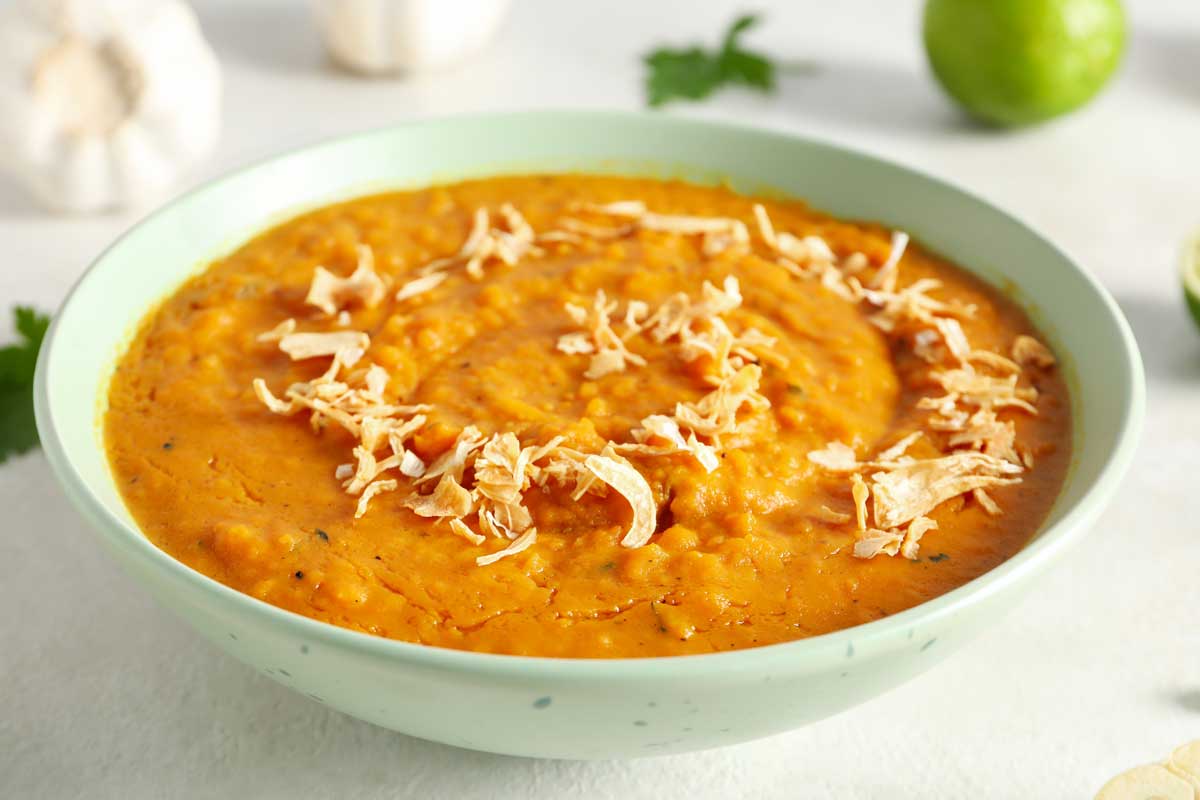 batatova polevka Krémová batátová polévka ozdobená sušenou cibulkou v světlé misce.