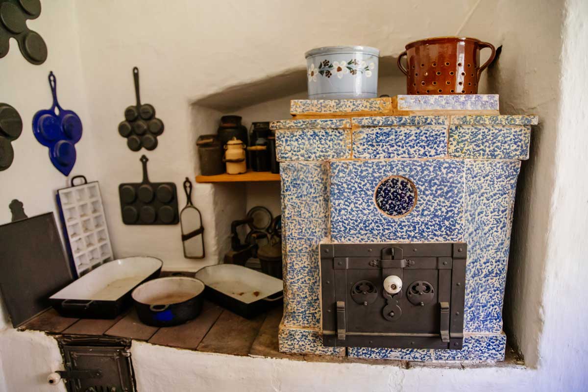 kamna Tradiční modrobílá kamna v historické kuchyni s litinovým nádobím.