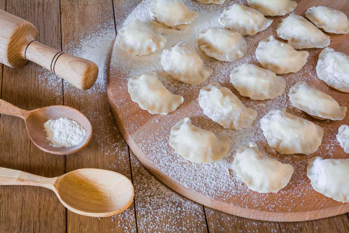 Domácí povidlové taštičky připravené k vaření na pomoučené dřevěné desce.