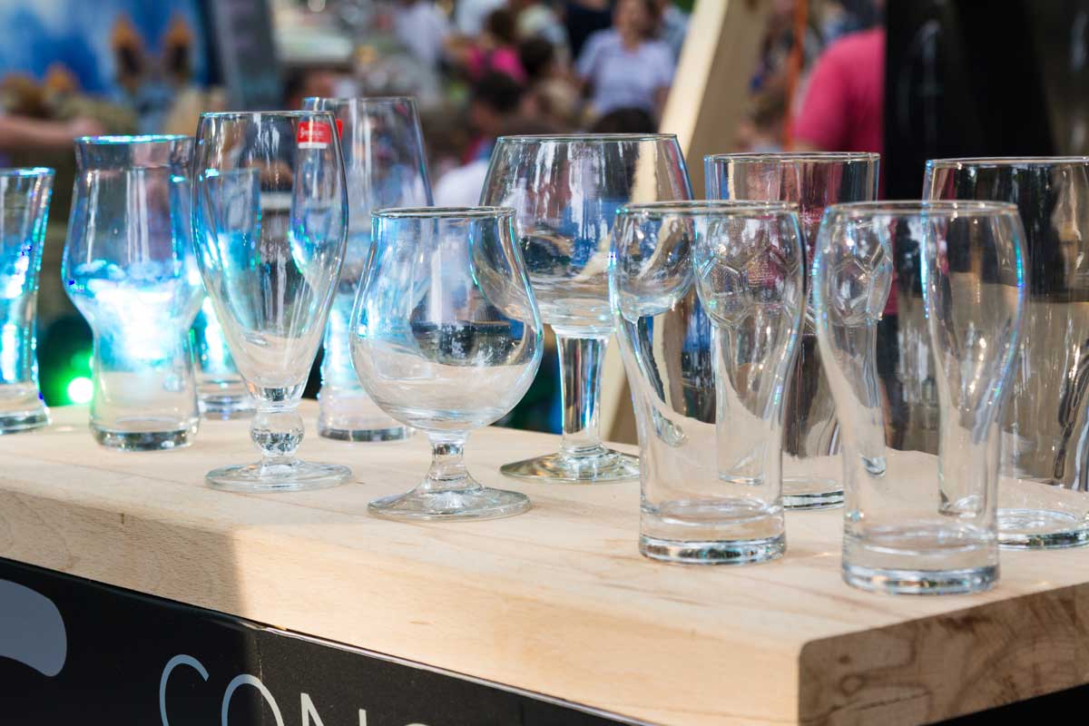 Různé typy čistých sklenic vystavené na dřevěné ploše na denním světle.