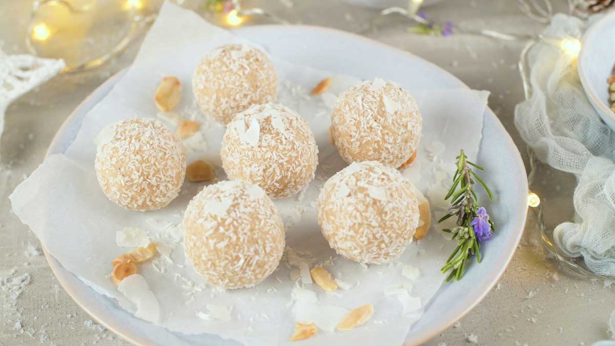 Kokosové nepečené kuličky obalené ve strouhaném kokosu na bílém talíři