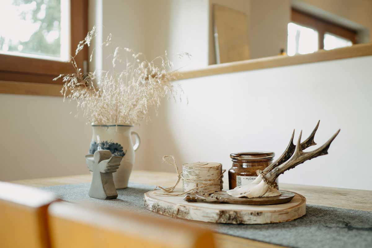 Detail lidových dekorací z přírodních materiálů na dřevěném stole v rekonstruované chatě