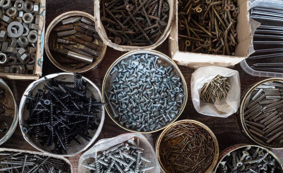 Krabičky a plechovky se tříděnými šroubky, matičkami a hřebíky jako jednoduchý dílenský organizér.