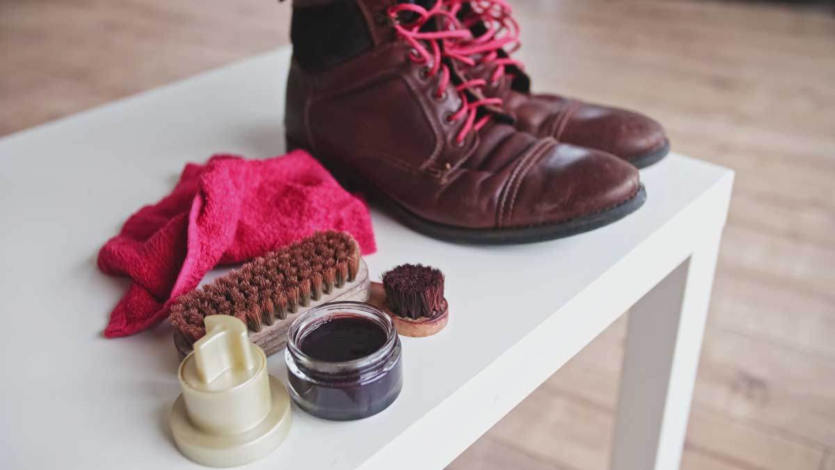 Zimní kožené boty s kartáčem, hadříkem a krémem na stole