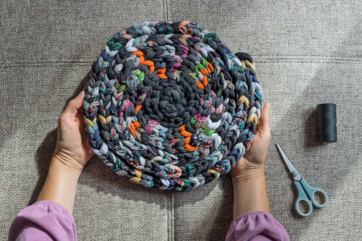 Ručně pletený kobereček z ponožek, kde je vidět každá barva a každý uzel.