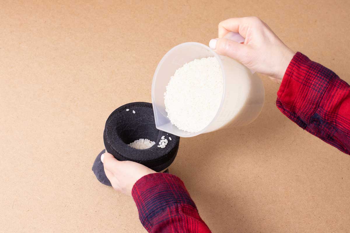 ryze v ponozce Ponožka naplněná rýží sloužící jako hřejivý polštářek pro úlevu od bolesti