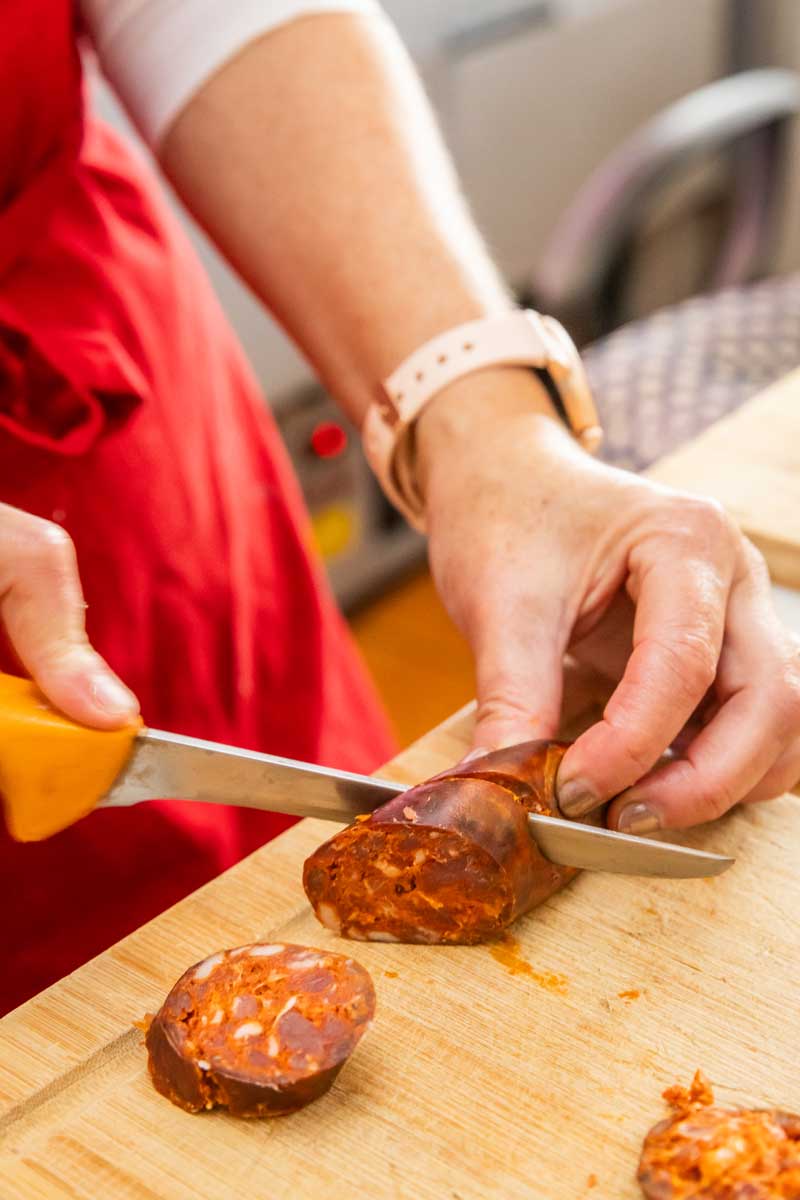 Domácí slovenská klobása na dřevěném prkénku, čerstvě nakrájené plátky a koření